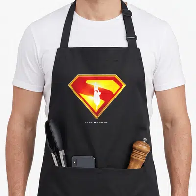 Exclusive novelty apron - Red yellow gold shield with white silhouette and Take Me Home text below — shown on a black cotton canvas apron against a white background
