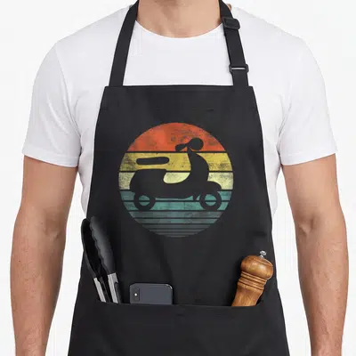 Driver scooter apron - Grey scooter silhouette on orange yellow teal grey striped circle background — shown on a black cotton canvas apron against a white background