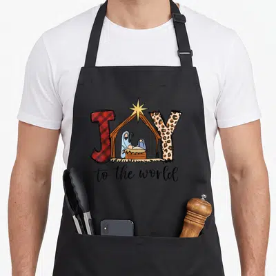 Joy baby christmas apron - JOY nativity scene with red plaid J, spotted Y, and script to the world text — shown on a black cotton canvas apron against a white background