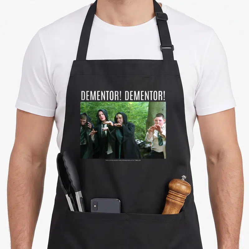 Draco potter apron - Dementor text above photo of four students in forest robes — shown on a black cotton canvas apron against a white background