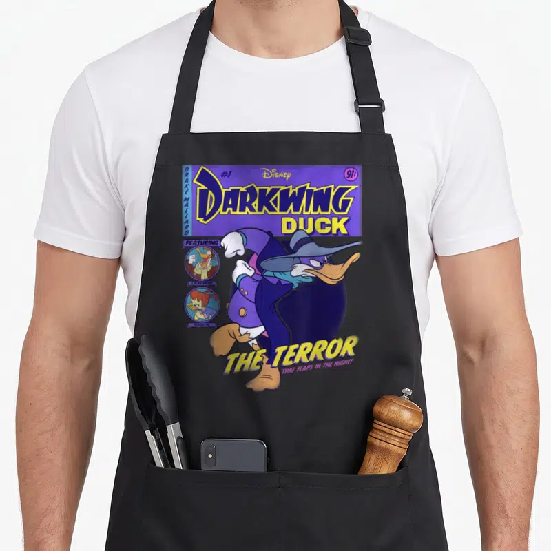 Darkwing duck apron - Vintage comic cover print of Darkwing Duck with Drake Mallard text and supporting character — shown on a black cotton canvas apron against a white background