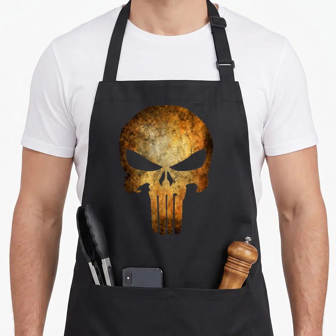 Universe skull apron - Weathered skull graphic in brown and gold tones on a black bib apron — shown on a black cotton canvas apron against a white background