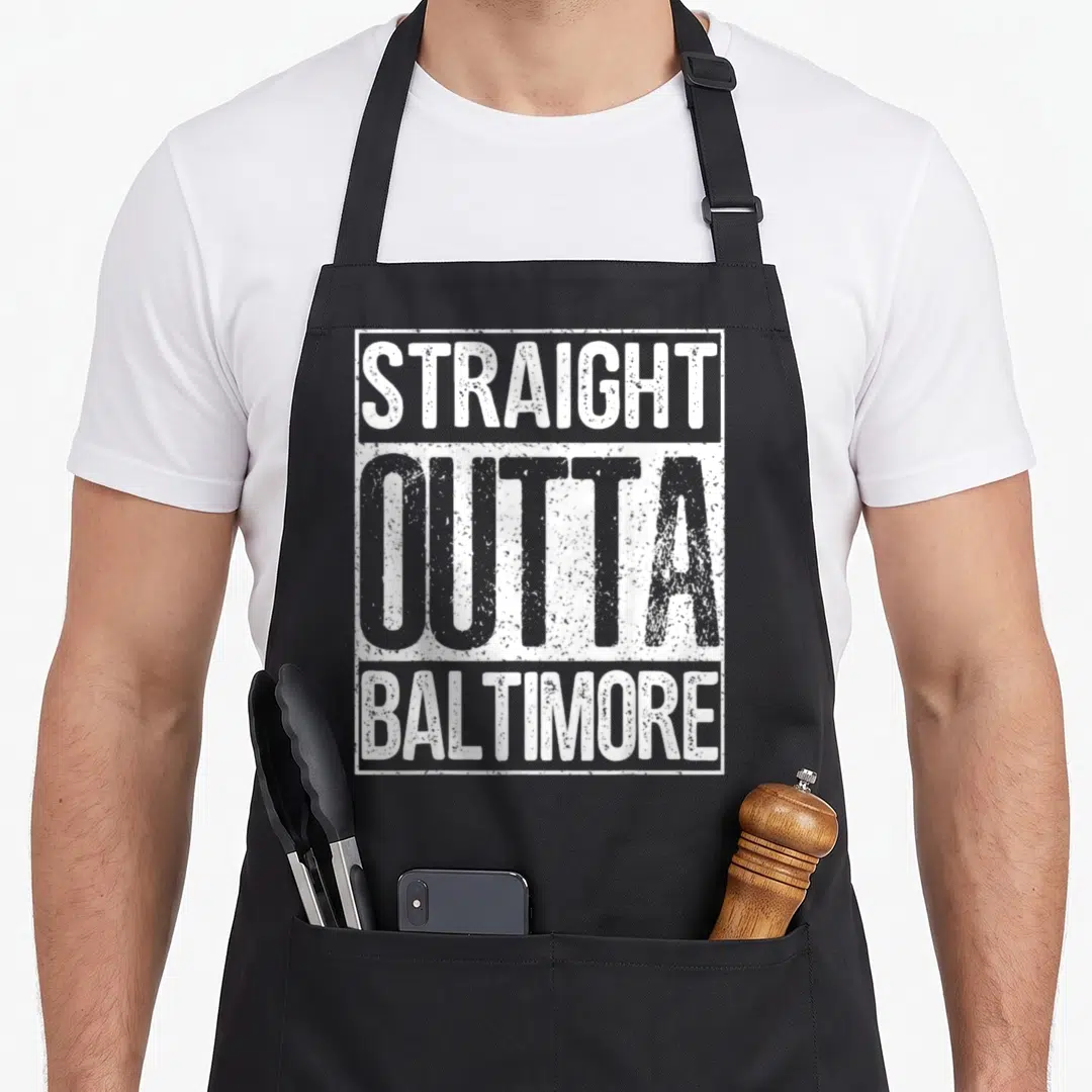 Straight baltimore apron - White distressed text reading STRAIGHT OUTTA BALTIMORE stacked vertically inside — shown on a black cotton canvas apron against a white background