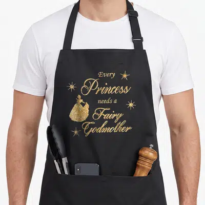 Princess fairy godmother apron - Gold glitter text Every Princess needs a Fairy Godmother with silhouette and stars — shown on a black cotton canvas apron against a white background