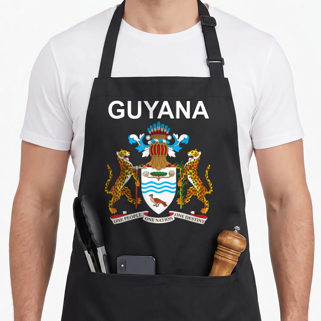 National guyana apron - Coat of Arms with two jaguars, shield, and motto One People One Nation One Destiny — shown on a black cotton canvas apron against a white background