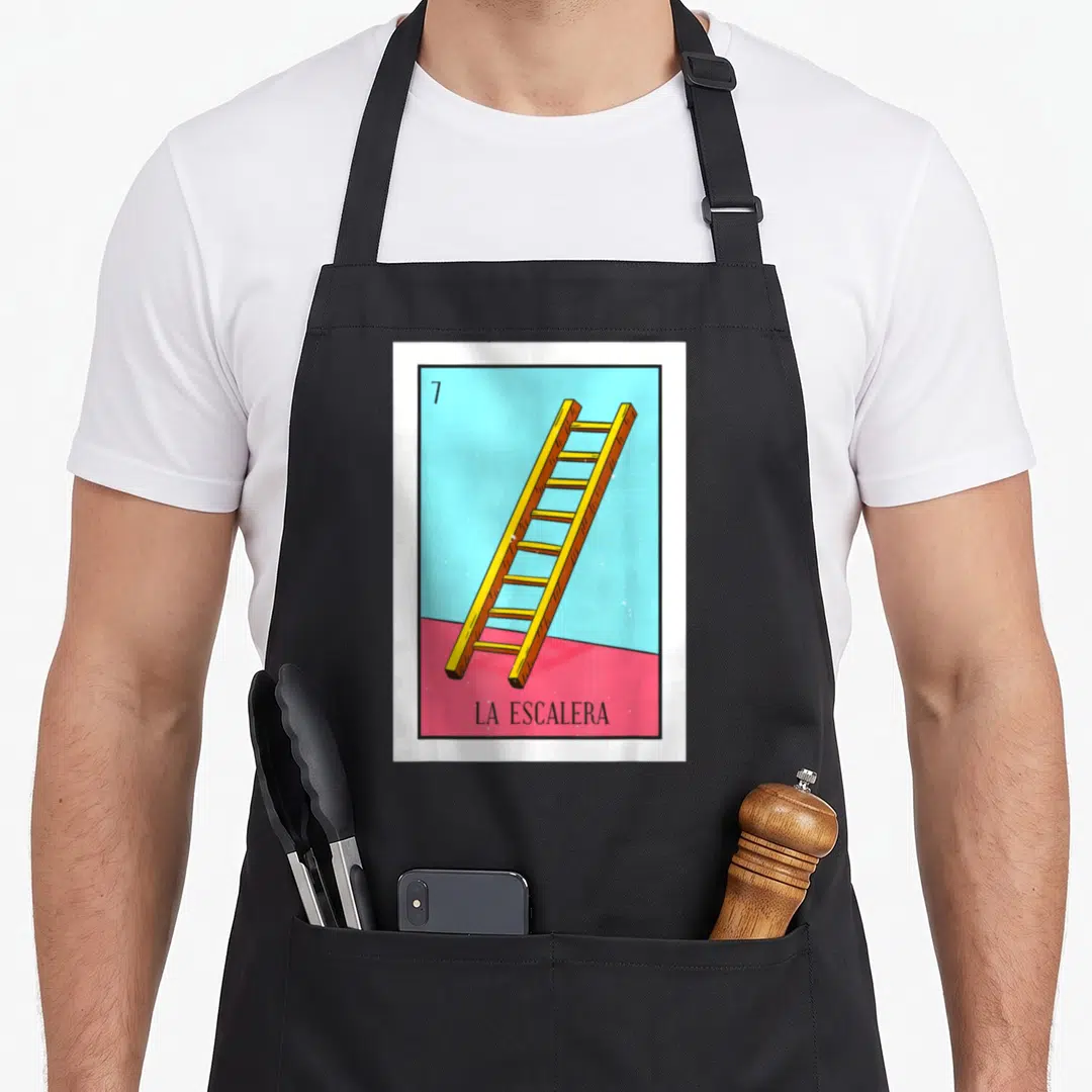 Escalera mexican apron - Yellow ladder on blue and pink background with number 7 and text LA ESCALERA — shown on a black cotton canvas apron against a white background