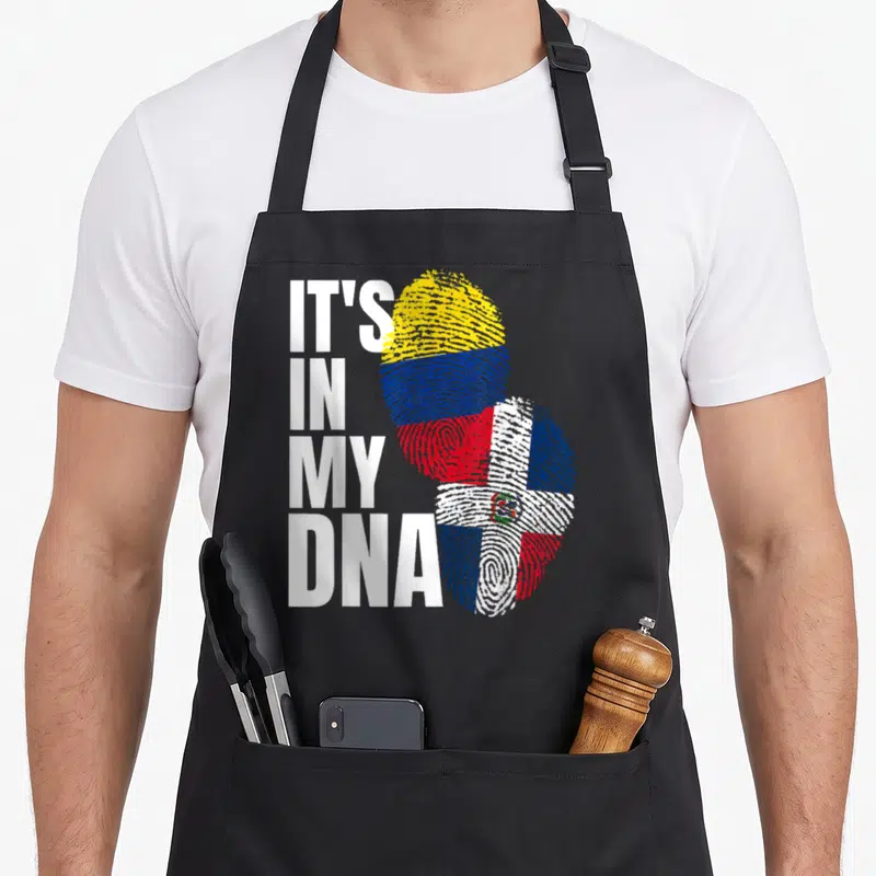 Mix heritage aprons - IT'S IN MY DNA text beside two fingerprints filled with Dominican and Colombian flag colors — shown on a black cotton canvas apron against a white background
