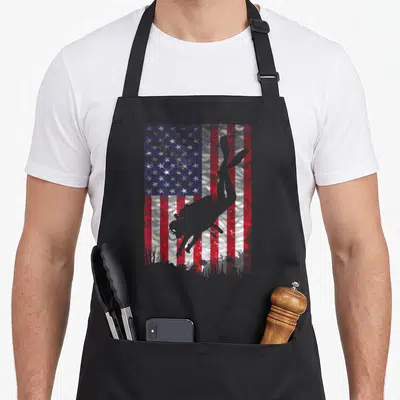 Coach diving apron - Grey scuba diver silhouette over distressed red white blue USA flag — shown on a black cotton canvas apron against a white background