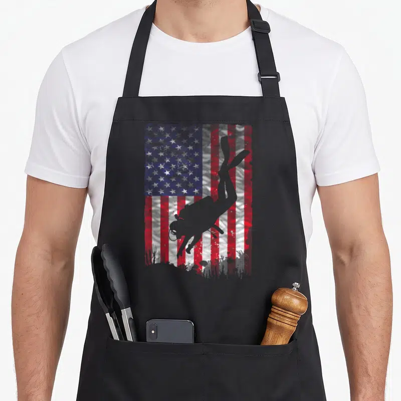 Coach diving apron - Grey scuba diver silhouette over distressed red white blue USA flag — shown on a black cotton canvas apron against a white background