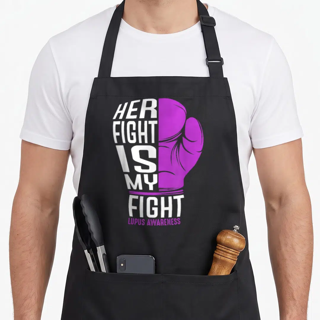 Fight lupus awareness apron - White text HER FIGHT IS MY FIGHT forming a boxing glove next to a purple glove drawing — shown on a black cotton canvas apron against a white background