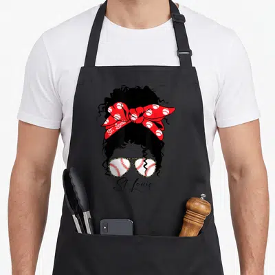 Louis messy aprons - Black woman silhouette with red baseball bow and cracked sunglasses reading St. Louis — shown on a black cotton canvas apron against a white background