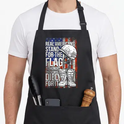 Veteran patriots apron - Distressed flag with helmet rifle boots silhouette and honor text — shown on a black cotton canvas apron against a white background