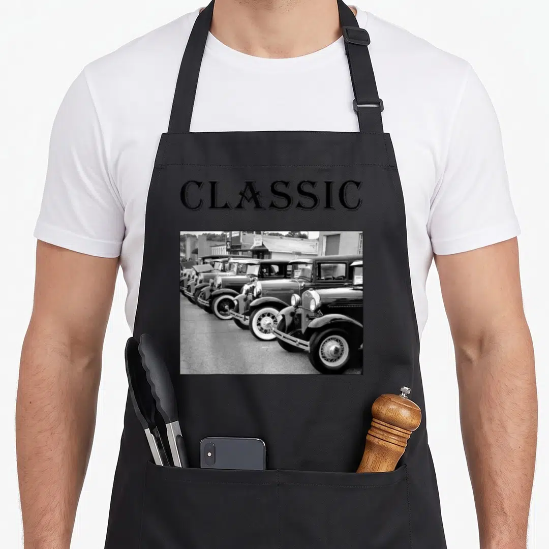 Father antique apron - CLASSIC text above b&w photo of vintage car row — shown on a black cotton canvas apron against a white background
