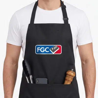 Fighting game aprons - Blue and red rectangle with white FGC text and grey arcade stick controller — shown on a black cotton canvas apron against a white background
