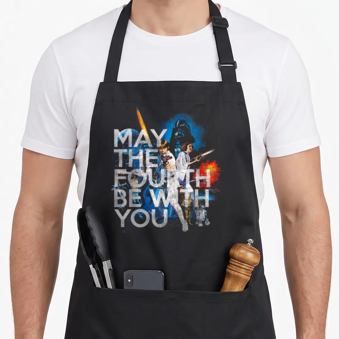 Fourth vintage may apron - MAY THE FOURTH BE WITH YOU text overlaid on watercolor Star Wars characters in blue white — shown on a black cotton canvas apron against a white background