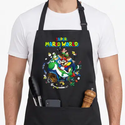 Around novelty apron - Super Mario World text above Mario riding Yoshi around a blue planet with game characters — shown on a black cotton canvas apron against a white background