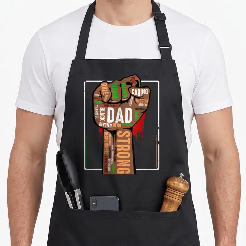Melanin pride african american aprons - Brown fist with DAD STRONG text and red drips inside white border — shown on a black cotton canvas apron against a white background