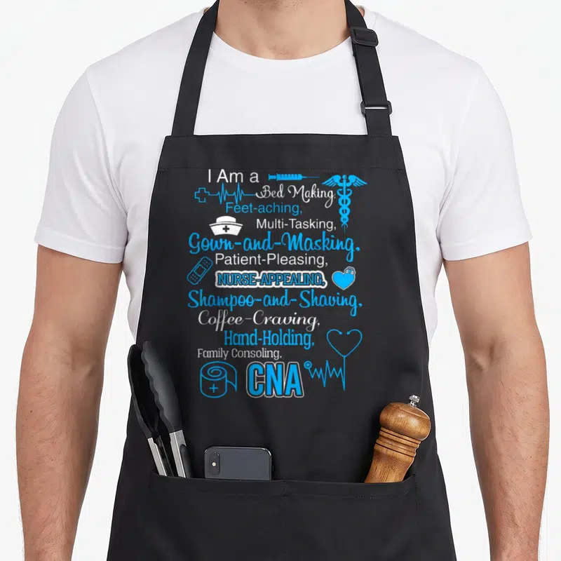 School nursing aprons - Stacked blue and white CNA job duties text with syringe, caduceus, bandage, toilet paper — shown on a black cotton canvas apron against a white background