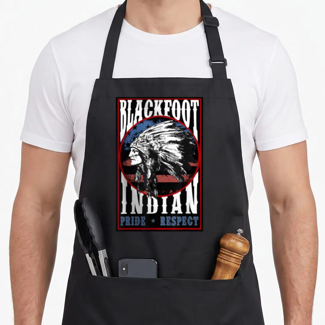 Blackfoot american flag apron - Distressed profile of man in headdress over circular flag with text Blackfoot Indian — shown on a black cotton canvas apron against a white background