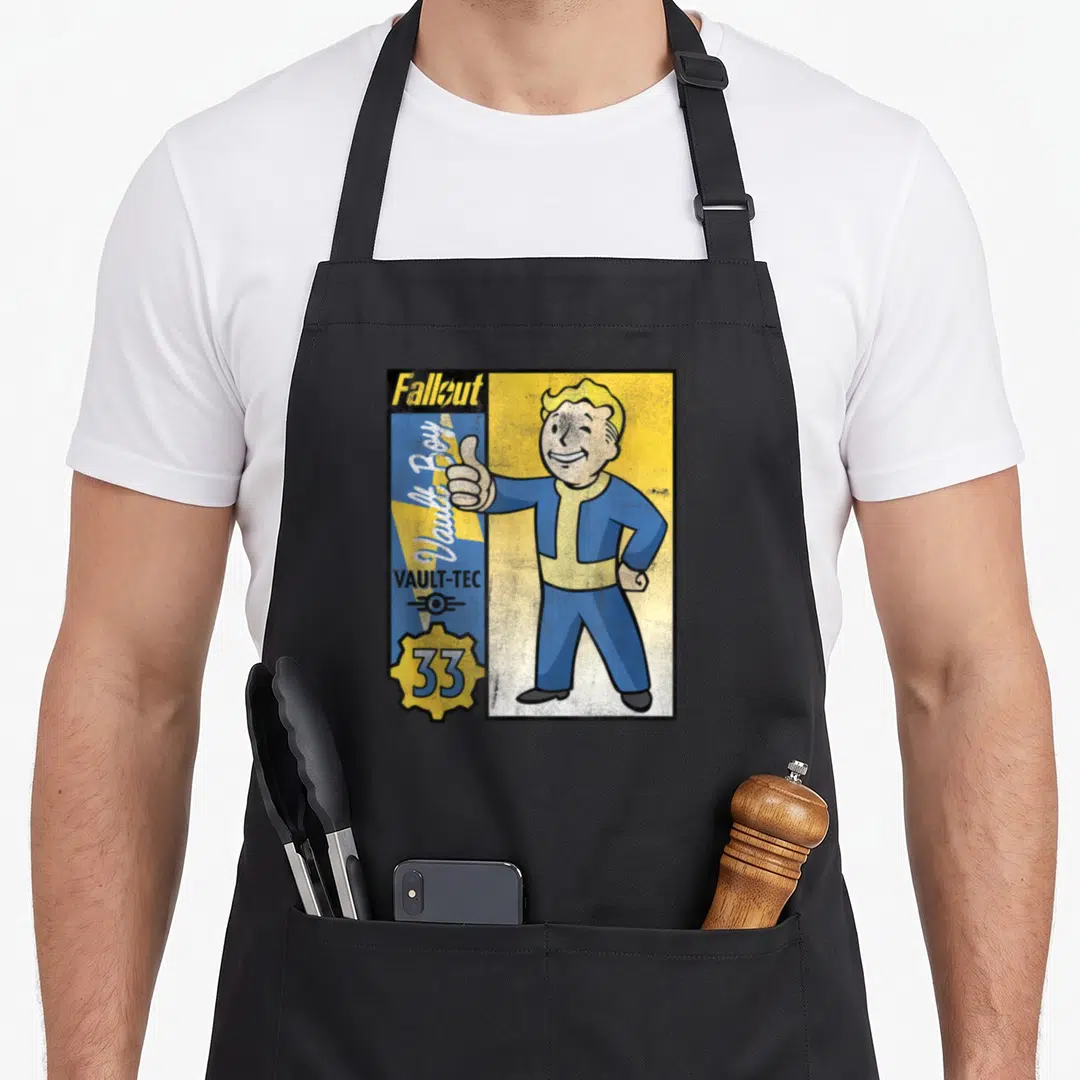 Tec show apron - Vault Boy cartoon character giving thumbs up beside blue yellow star with VAULT-TEC text — shown on a black cotton canvas apron against a white background