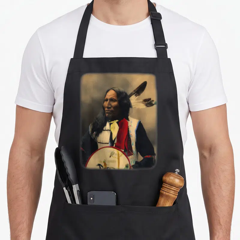 Oglala native american apron - Colorized portrait of a man holding a painted drum with red and yellow accents — shown on a black cotton canvas apron against a white background
