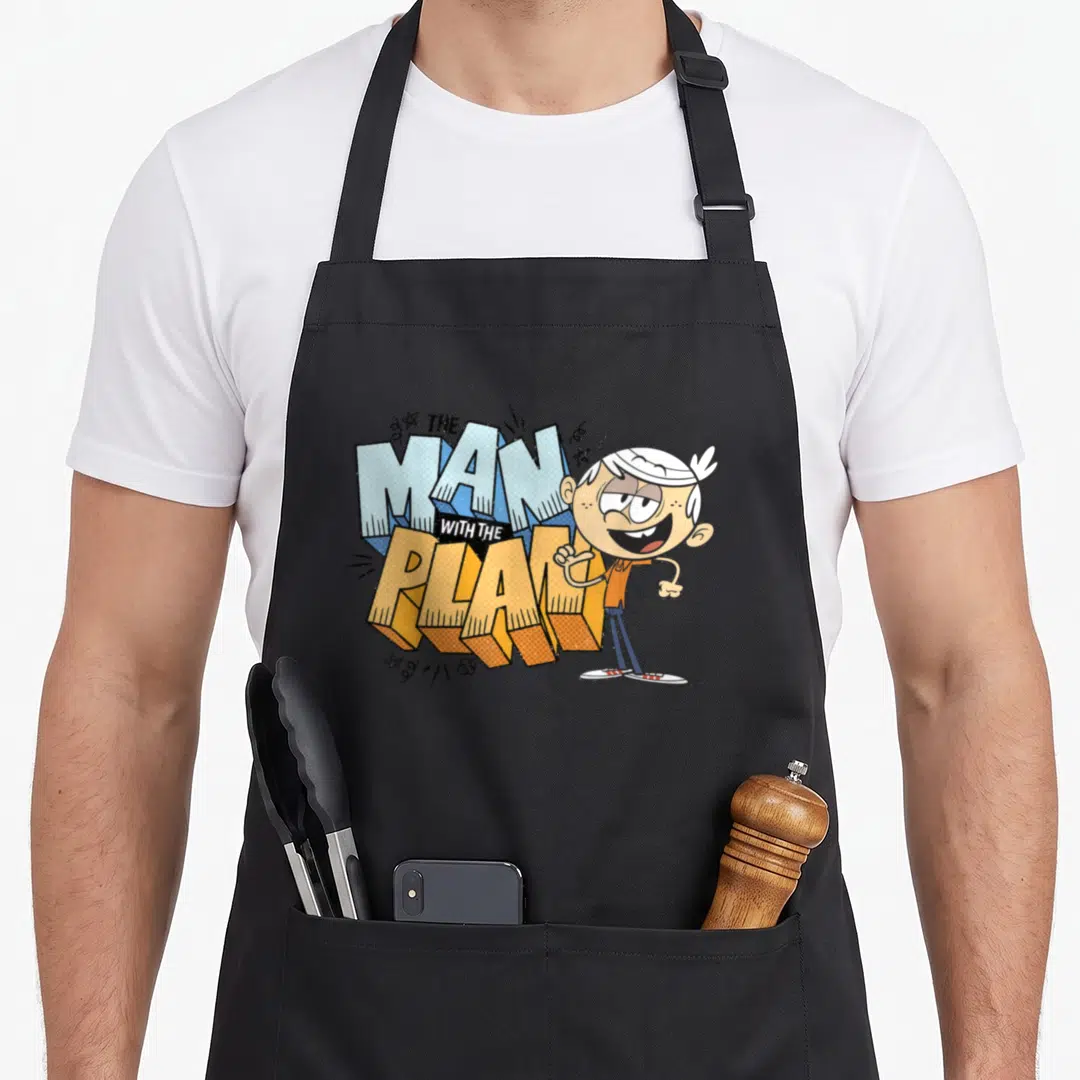 Plan novelty apron - Cartoon boy standing beside large 3D text reading THE MAN WITH THE PLAN in blue and orange — shown on a black cotton canvas apron against a white background