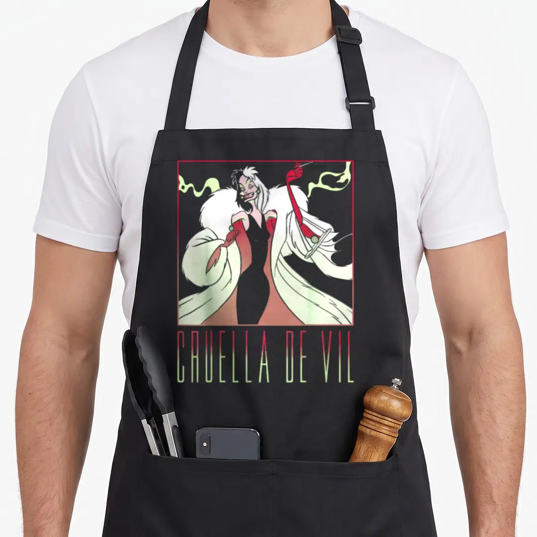 Dalmatian box apron - Cruella de Vil character in red square frame with gradient text below — shown on a black cotton canvas apron against a white background