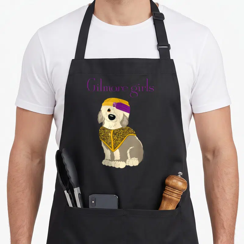 Paul gilmore girls apron - Cartoon dog in yellow turban and cape below purple Gilmore girls text on grey background — shown on a black cotton canvas apron against a white background