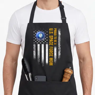 Space american flag apron - Distressed white flag with US Space Force seal and vertical orange text — shown on a black cotton canvas apron against a white background