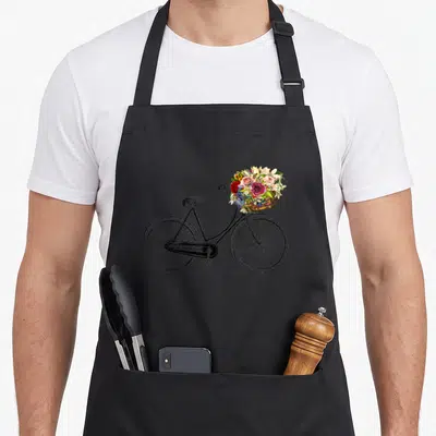 Sketch bike apron - Black bicycle with basket holding red pink yellow and brown flowers — shown on a black cotton canvas apron against a white background