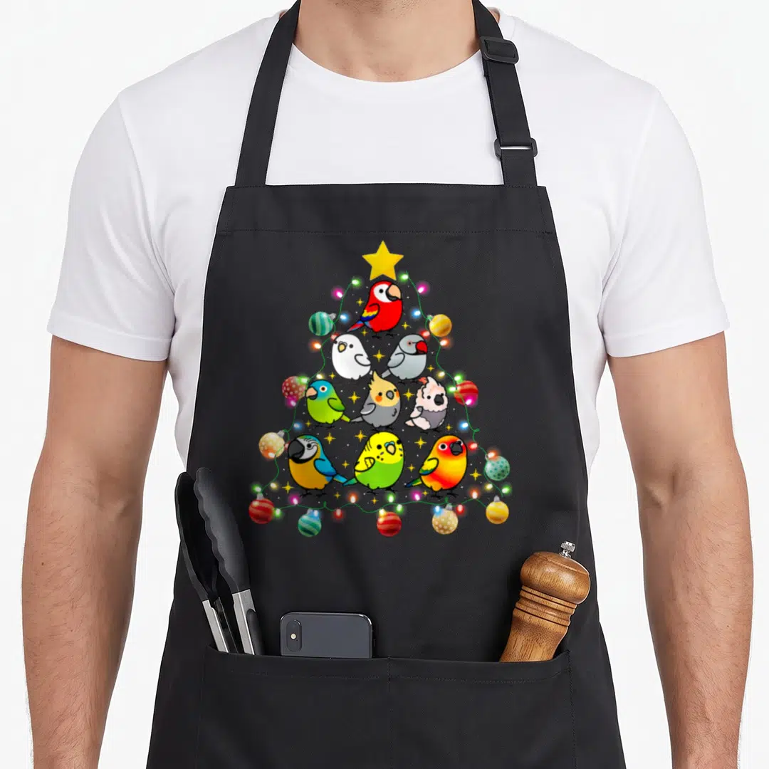 Parrot christmas tree apron - Nine cartoon parrots arranged in a triangle with a yellow star and string lights — shown on a black cotton canvas apron against a white background