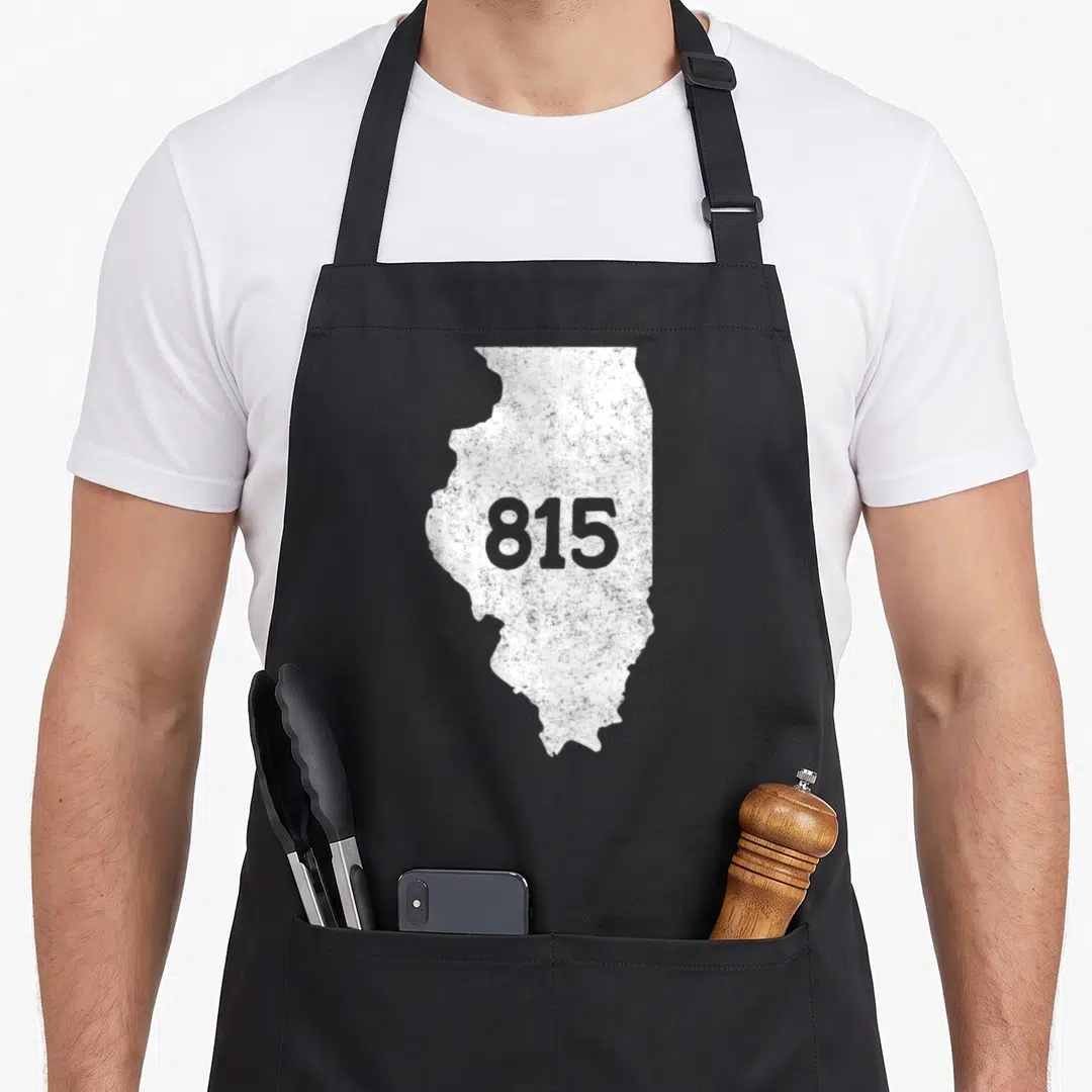 Illinois prairie apron - White Illinois map outline with grey 815 number in center — shown on a black cotton canvas apron against a white background