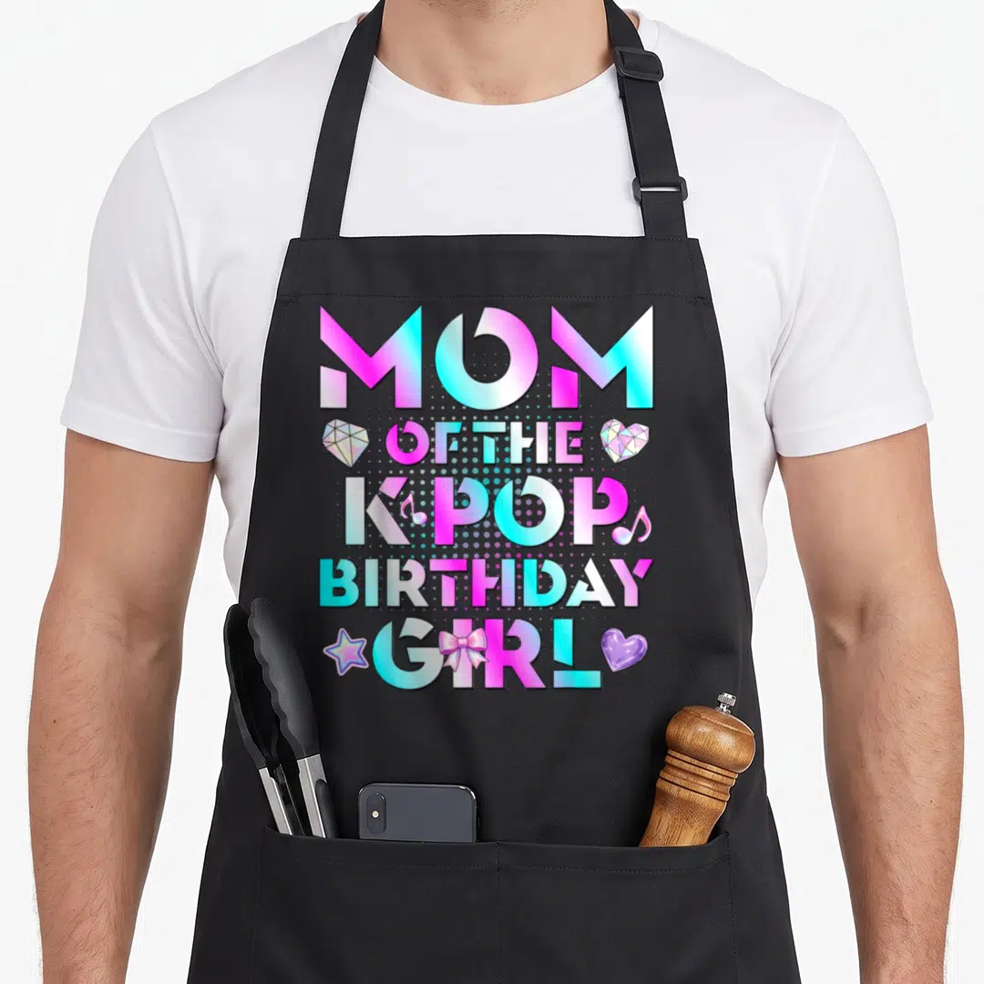 Birthday music korean apron - MOM OF THE KPOP BIRTHDAY GIRL text with pink cyan purple graphics — shown on a black cotton canvas apron against a white background