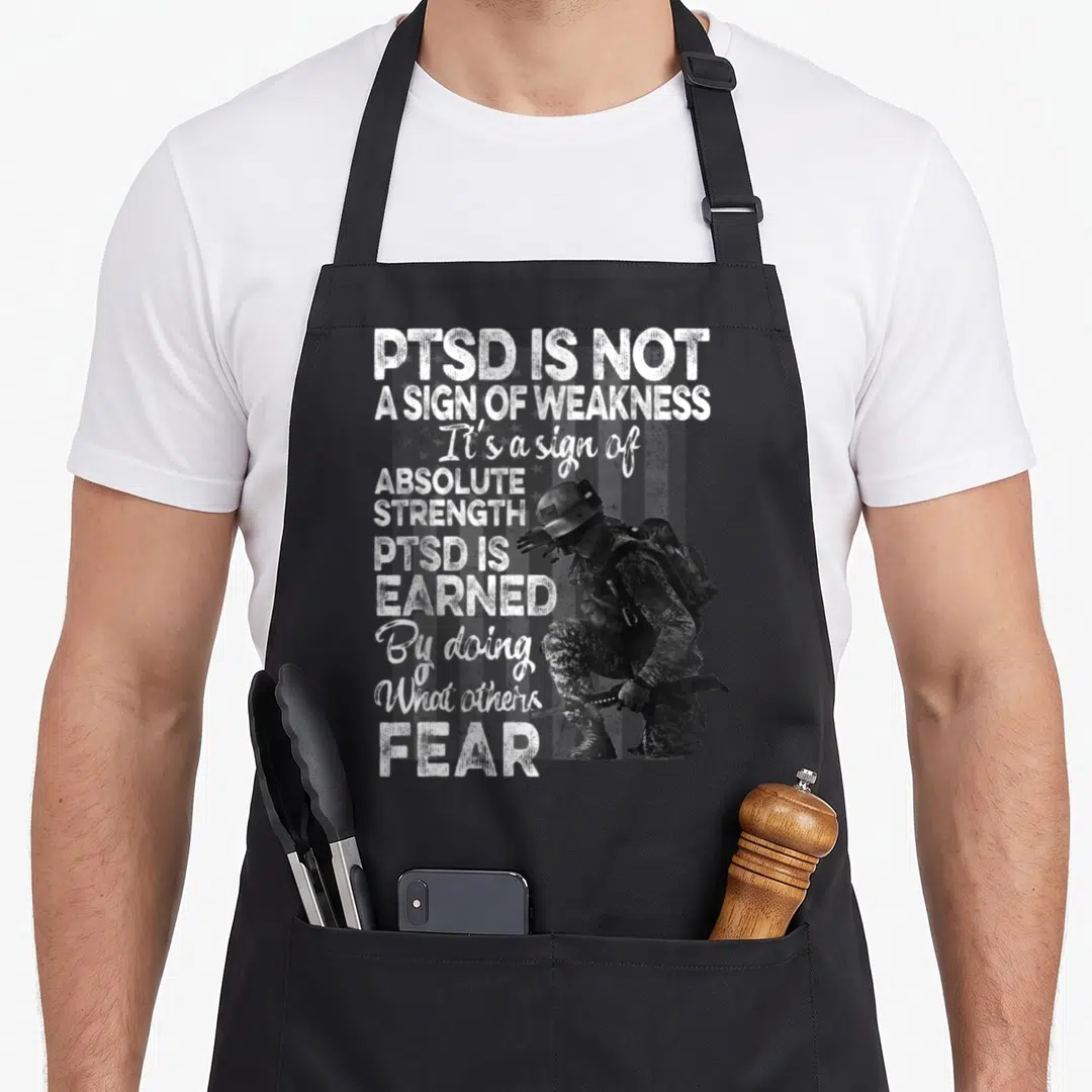 Post ptsd awareness apron - Kneeling soldier with PTSD strength quote and faded flag background — shown on a black cotton canvas apron against a white background