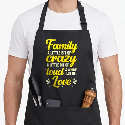 Bit gathering apron - Yellow and white stacked text reading Family A Little Bit Of Crazy surrounded by dots — shown on a black cotton canvas apron against a white background