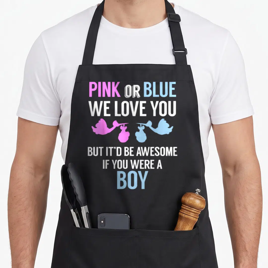 Blue gender reveal apron or apron - Two storks carrying pink and blue bundles between stacked text about wanting a boy — shown on a black cotton canvas apron against a white background
