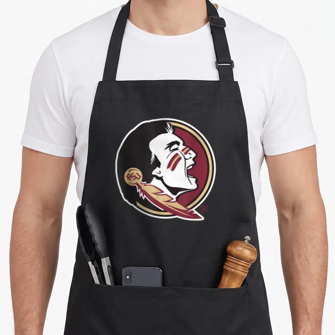State florida apron - Cartoon profile of a man in a maroon and gold circle with a feather overlay — shown on a black cotton canvas apron against a white background
