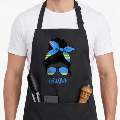 Caribbean messy aprons - Woman silhouette with Aruba flag bun, sunglasses, and blue text ARUBA — shown on a black cotton canvas apron against a white background