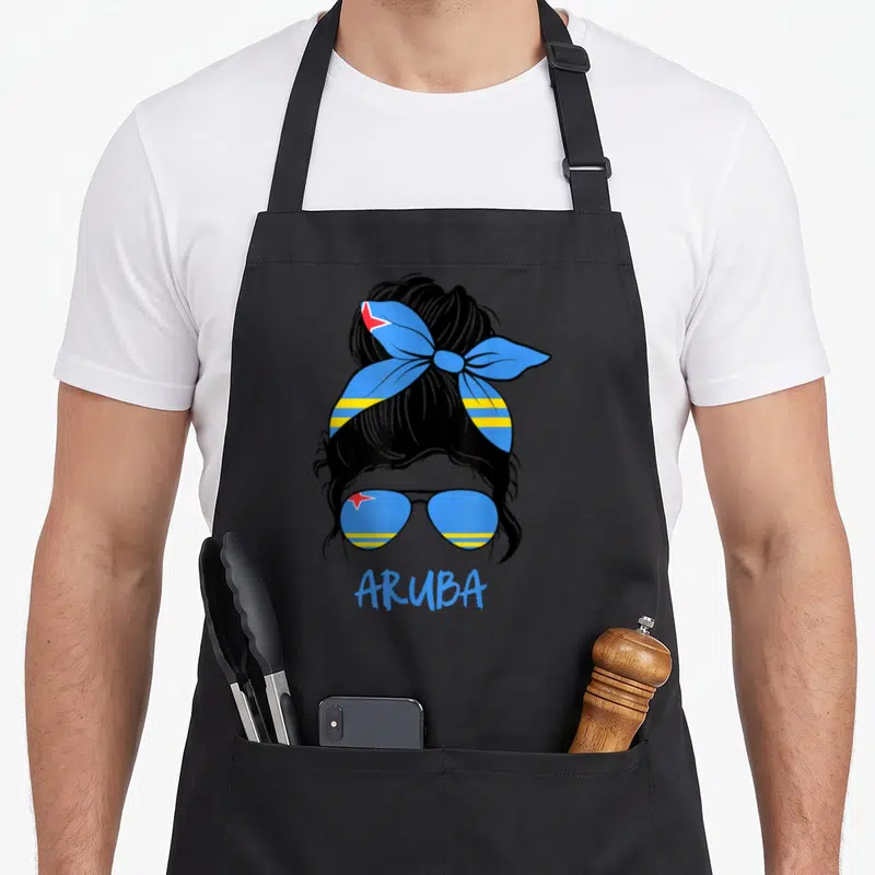 Caribbean messy aprons - Woman silhouette with Aruba flag bun, sunglasses, and blue text ARUBA — shown on a black cotton canvas apron against a white background