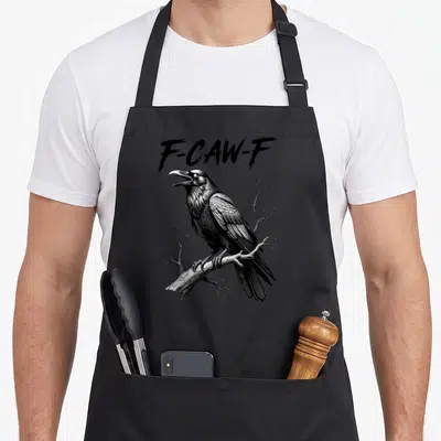 Dark halloween apron - F-CAW-F text above a realistic crow perched on a bare branch in black and grey — shown on a black cotton canvas apron against a white background