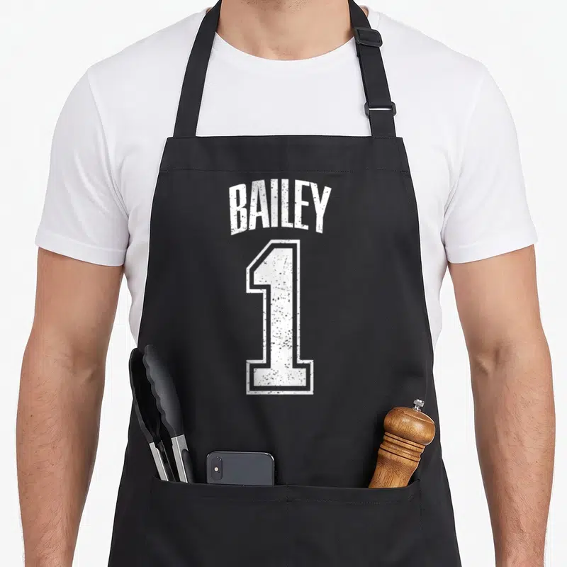 Supporter baileys apron - White distressed BAILEY text arched over a large number 1 — shown on a black cotton canvas apron against a white background