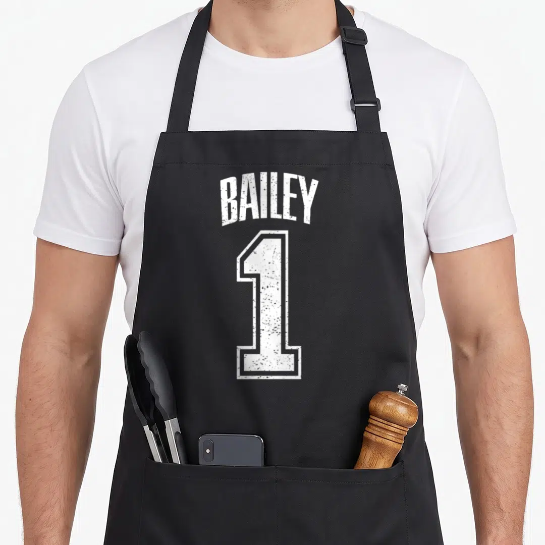 Supporter baileys apron - White distressed BAILEY text arched over a large number 1 — shown on a black cotton canvas apron against a white background