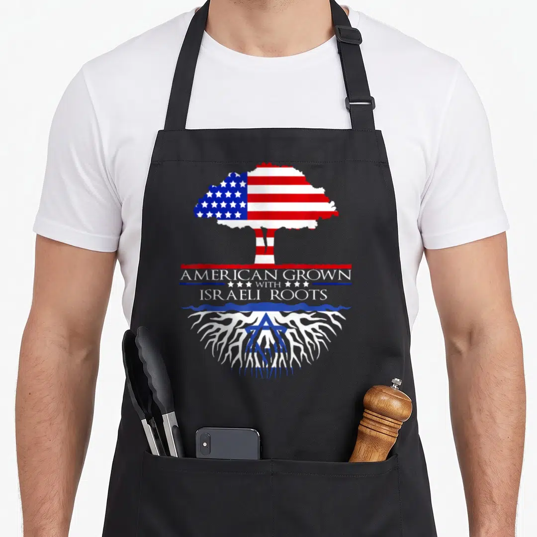 Israeli root american flag apron - Tree with US flag canopy and Israeli star of David roots below text — shown on a black cotton canvas apron against a white background