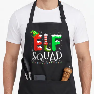 Pajamas elf apron - Stylized ELF SQUAD text with elf hat shoe letters and colorful lights — shown on a black cotton canvas apron against a white background