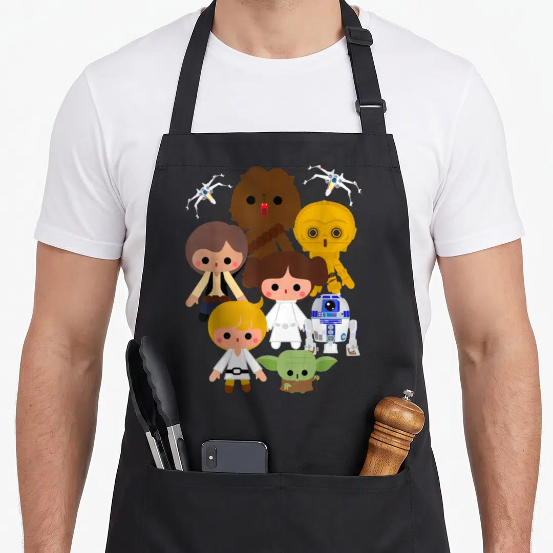 Funny heroe kawaii apron - Chibi Star Wars characters and two X-wings in brown, gold, white, blue, green, and red — shown on a black cotton canvas apron against a white background