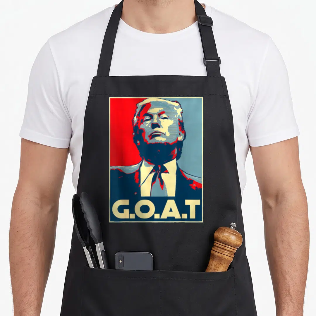Trump goat apron - Stylized portrait of Donald Trump above G.O.A.T text in red blue beige — shown on a black cotton canvas apron against a white background
