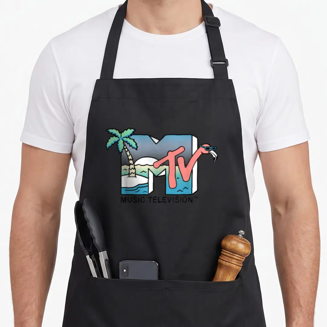 Mtv kitchen island apron - Pink flamingo in sunglasses inside blue M with palm tree and MUSIC TELEVISION text — shown on a black cotton canvas apron against a white background