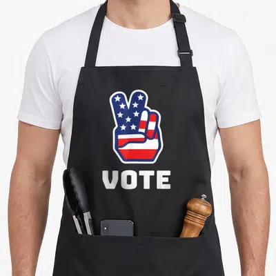 Peace stripe apron - Cartoon hand peace sign in stars and stripes above VOTE text — shown on a black cotton canvas apron against a white background