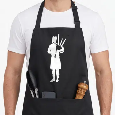 Player bagpipes apron - White silhouette of a bagpiper standing alone on a black bib apron — shown on a black cotton canvas apron against a white background
