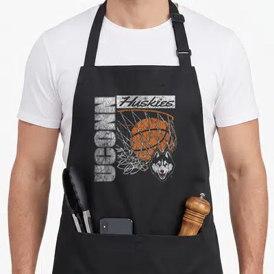 90s husky apron - Distressed UCONN Huskies basketball print with orange ball, white net, grey husky head — shown on a black cotton canvas apron against a white background